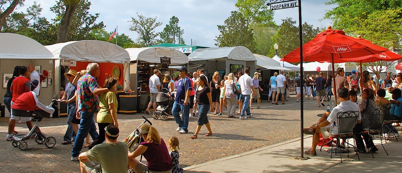 People walking on Park Ave and shopping at the vendor tents on a sunny day.