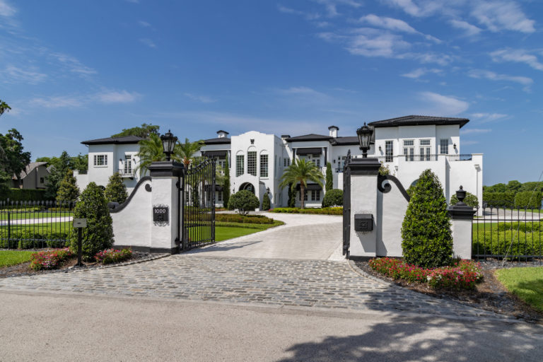 White home with a white and black gate and green grass.