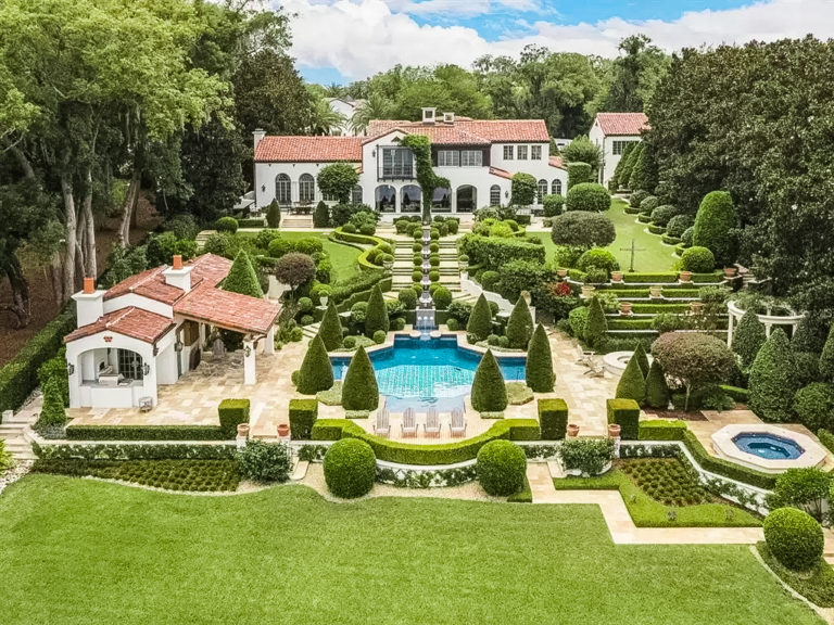 White House with red roof and green landscaping that surrounds a blue pool