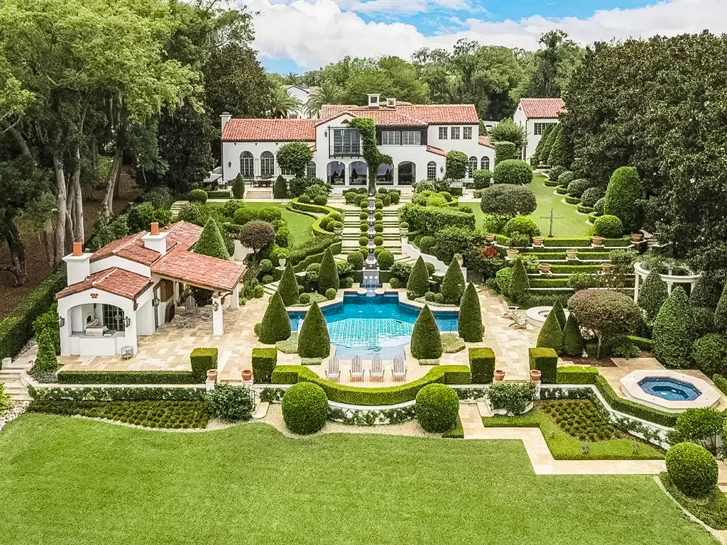 White House with red roof and green landscaping that surrounds a blue pool